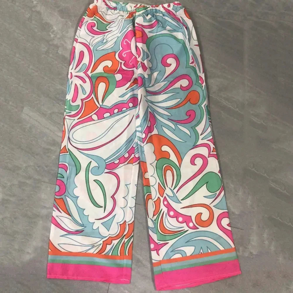 Colorful patterned wide-leg pants with pink, green, orange, and aqua swirls on gray floor