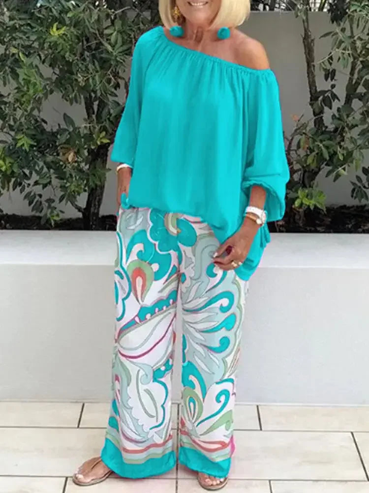 Woman wearing turquoise off-shoulder blouse and patterned wide-leg pants, MY$TOAR fashion