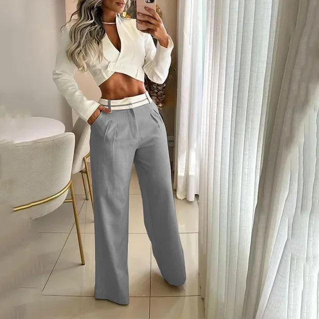 Woman wearing luxury MY$TOAR grey wide-leg pants and white cropped blazer, stylish indoor setting